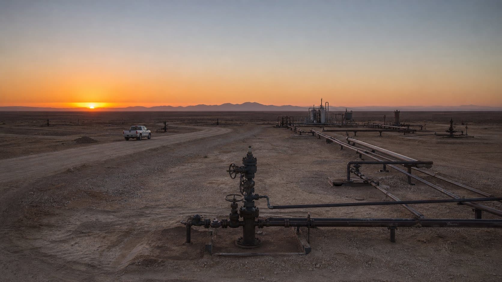 Desert oilfield with wellheads at sunset